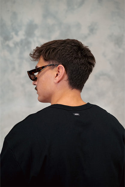  Male wearing TMJ Apparel 1993 Tee in Black showing the small woven TMJ tag on back of collar