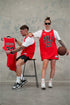 Male & female wearing Chicago Bulls inspired limited edition red TMJ Apparel 2023 Basketball Jersey showing "TMJ" with the number "23" in black on the front.