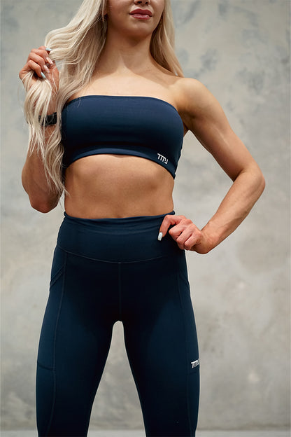 Female wearing TMJ Apparel Camilla Bandeau in Navy showing the embroidered TMJ Performance logo on bottom left front. Pairing with Sculpt Tights V2 in Navy.