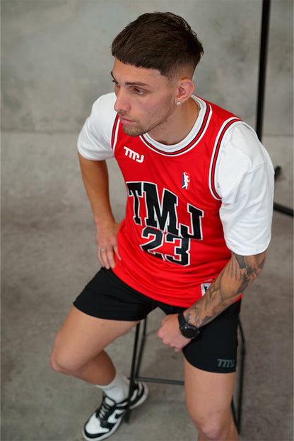 Male wearing Chicago Bulls inspired limited edition red TMJ Apparel 2023 Basketball Jersey showing &quot;TMJ&quot; with the number &quot;23&quot; in black on the front.