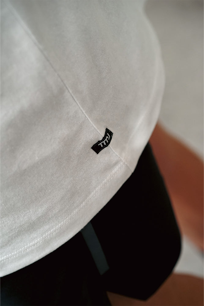 Close up of TMJ Apparel 1993 Tee in Dune showing the small TMJ label on left hip side seam.