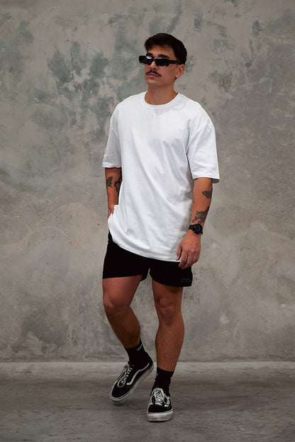 Male wearing TMJ Apparel 1993 in the colour White showing the minimal design with a small 3D “TMJAPPARELCO” on front left chest.