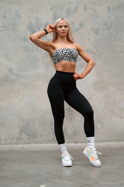 Female wearing TMJ Apparel Camilla Bandeau in Black showing the embroidered TMJ Performance logo on bottom left front. Pairing with Sculpt Tights V2 in Black.