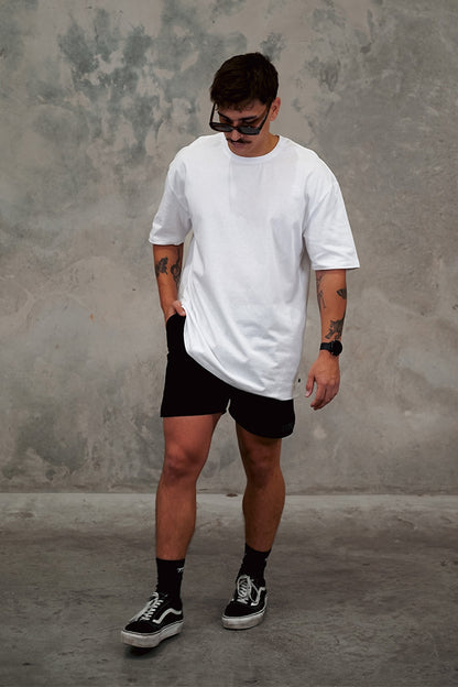 Male wearing TMJ Apparel 1993 in the colour White showing the minimal design with a small 3D “TMJAPPARELCO” on front left chest.