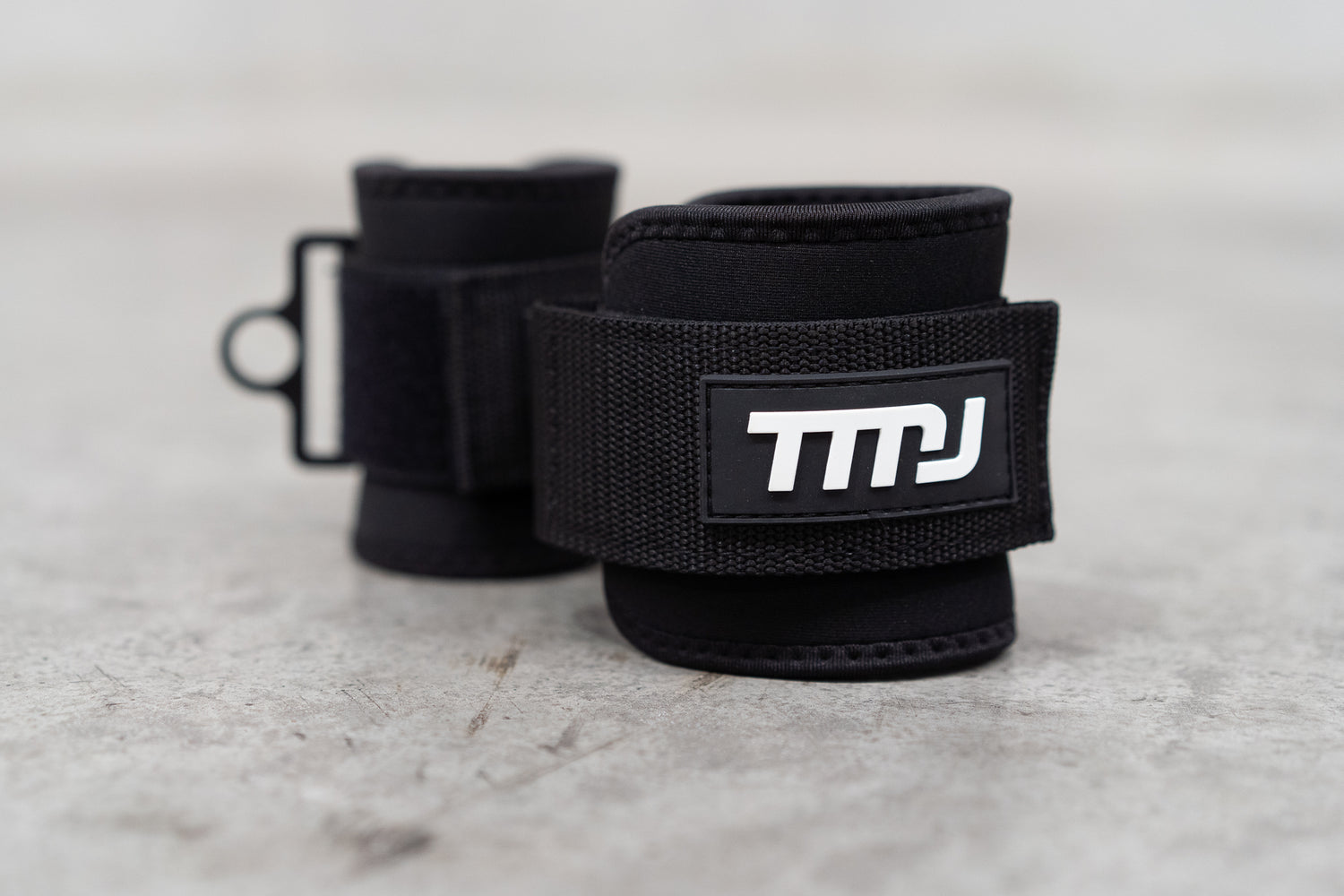 Black TMJ Apparel Ankle Straps showing white rubber embossed &quot;TMJ&quot; logo sewn on the front.