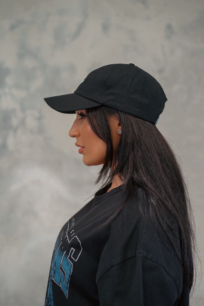 Female wearing black Chino Cap showing the side of cap.