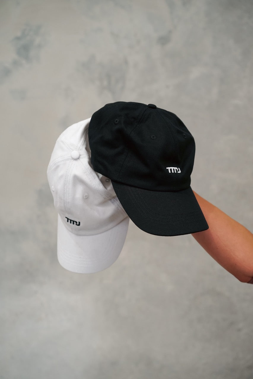 Image of both the black &amp; white Chino Caps showing the minimal design with small &quot;TMJ&quot; logo on front of cap.