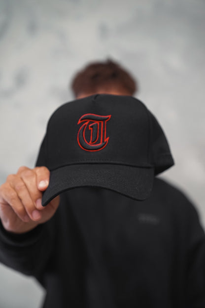 Male holding Black TMJ Apparel 9PHIFTY A-Frame Snapback Hat with Black 3D Embroidered Magna Carta T Logo with red outline on the front.