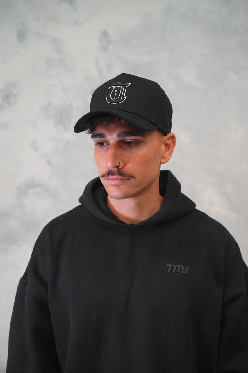 Male wearing Black TMJ Apparel 9PHIFTY A-Frame Snapback Hat with Black 3D Embroidered Magna Carta T Logo with white outline on the front.