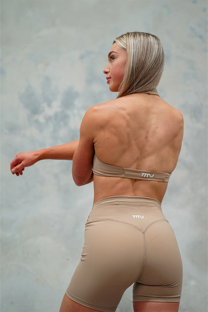 Female wearing Amy Twist Front Bra and Mimi Shorts in Nude showing the halter-neck open back design of the bra and squat-proof design of the shorts.