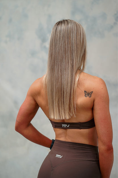 Female wearing Amy Twist Front Bra and Mimi Shorts in Dark Brown showing the halter-neck open back design of the bra.