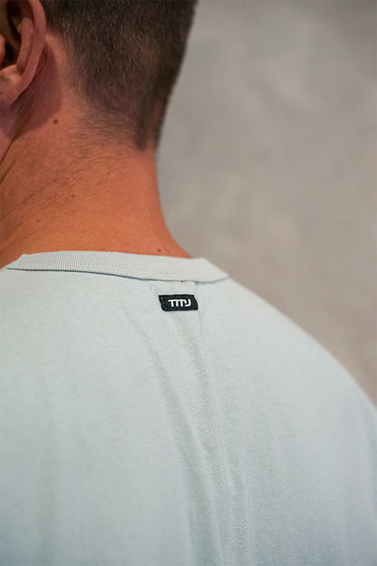 Male wearing TMJ Apparel Athleticulture Tee in Powder Blue showing the small TMJ tag on back of collar