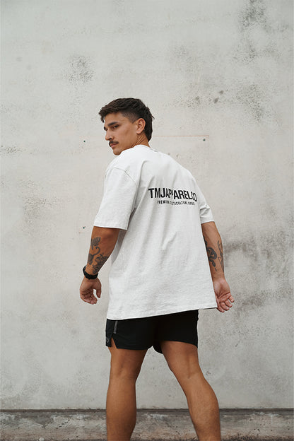 Male wearing TMJ Apparel Athleticulture Tee in Light Grey showing the back of the shirt with white text saying TMJAPPARELCO Premium Athleticulture Goods in the the middle centre of back