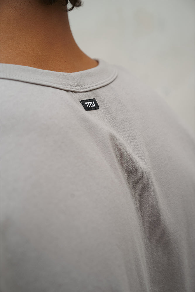 Male wearing TMJ Apparel Athleticulture Tee in Dune showing the small TMJ tag on back of collar